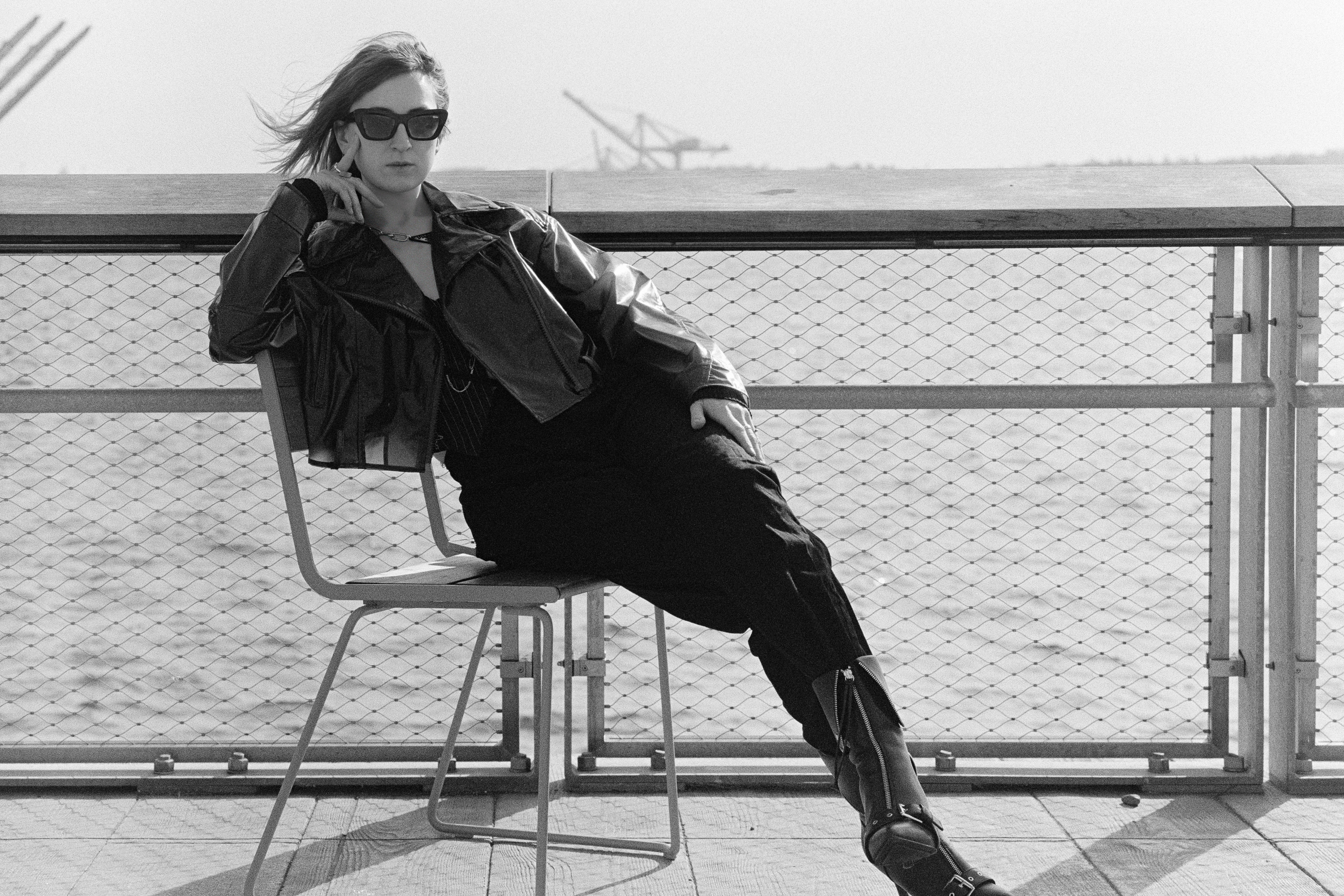 Leather jacket, sunglasses, seated at the rail